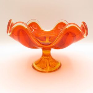 orange glass dish on a pedestal with wavey edge